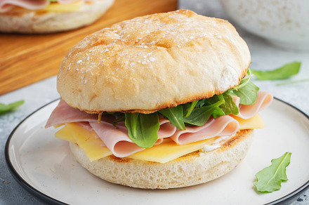 Two homemade sandwiches with ham, cheese and arugula on a concrete table., a Food & Drink Photo by Budarinphoto