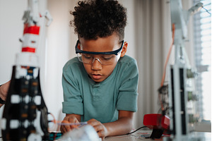 Focused boy working on small robot, a School & Education Photo by HalfPoint