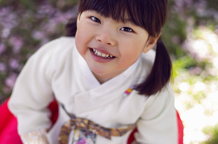 Korean girl child in a national costume walks in a garden with cherry blossoms, a Person Photo by SaulichPhoto