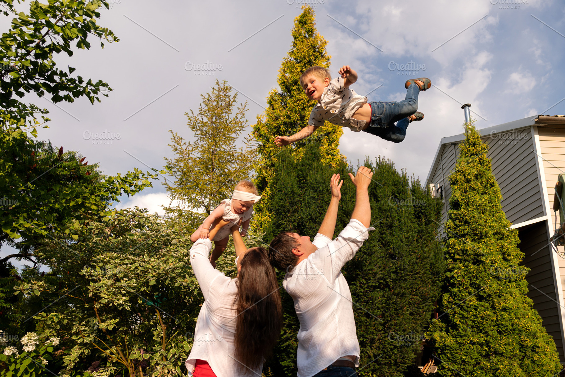 Father tosses laughing son skyward, a Person Photo by Elena Vagengeim