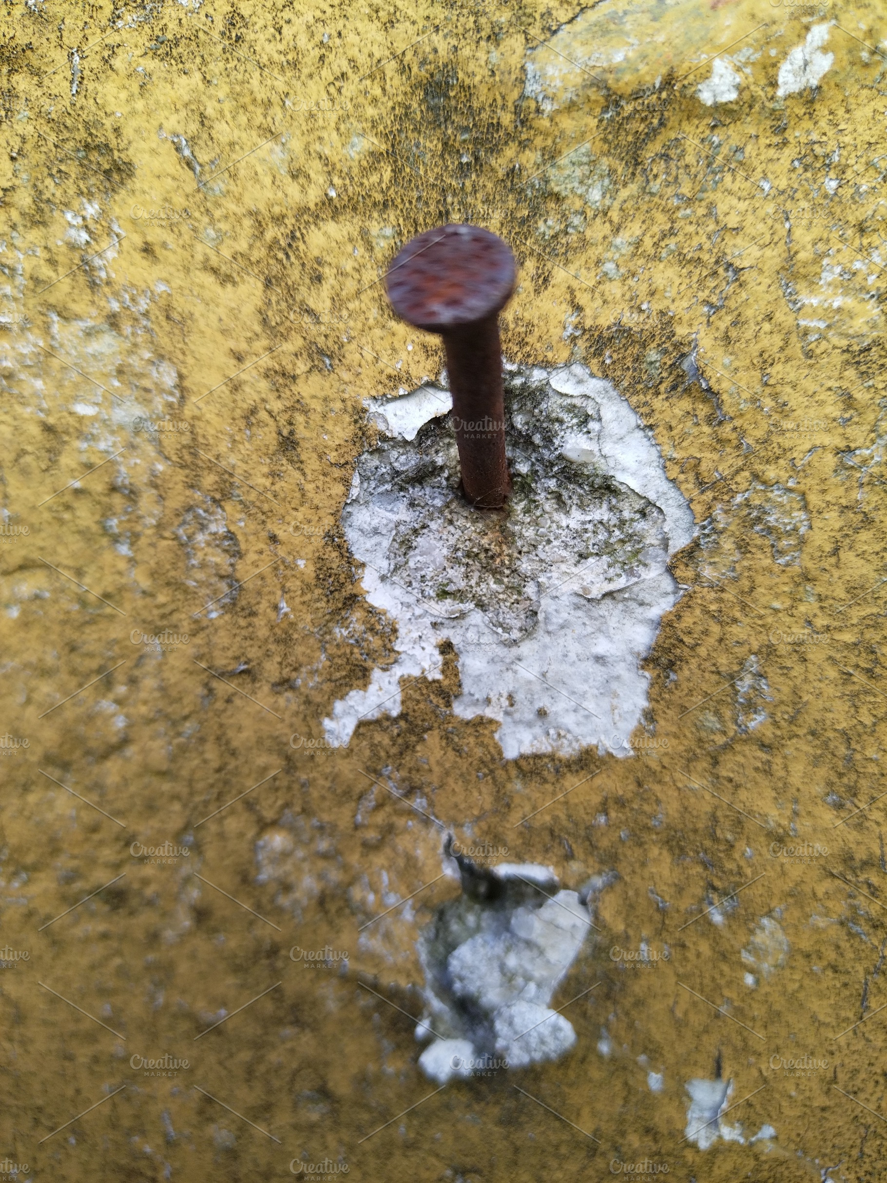Rusty nail embedded in peeling yellow wall, a Background Photo by DanFLCreativo