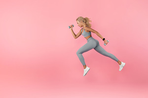 Young Woman Running With Dumbbells Isolated On Studio Background, a Photo by Prostock-Studio