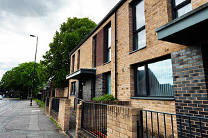 Modern brick apartment building and residential street with tree