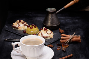 A cup of coffee with desserts, a cezve and cinnamon on a black b, a Food & Drink Photo by ndanko