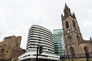 Contrast between historic church tower and modern office buildin