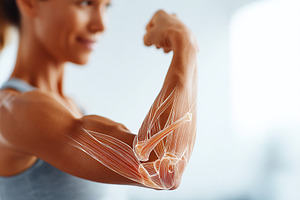 Woman flexes her bicep to showcase muscle anatomy in a bright indoor setting, a Sports & Recreation Photo by AlyaAnd