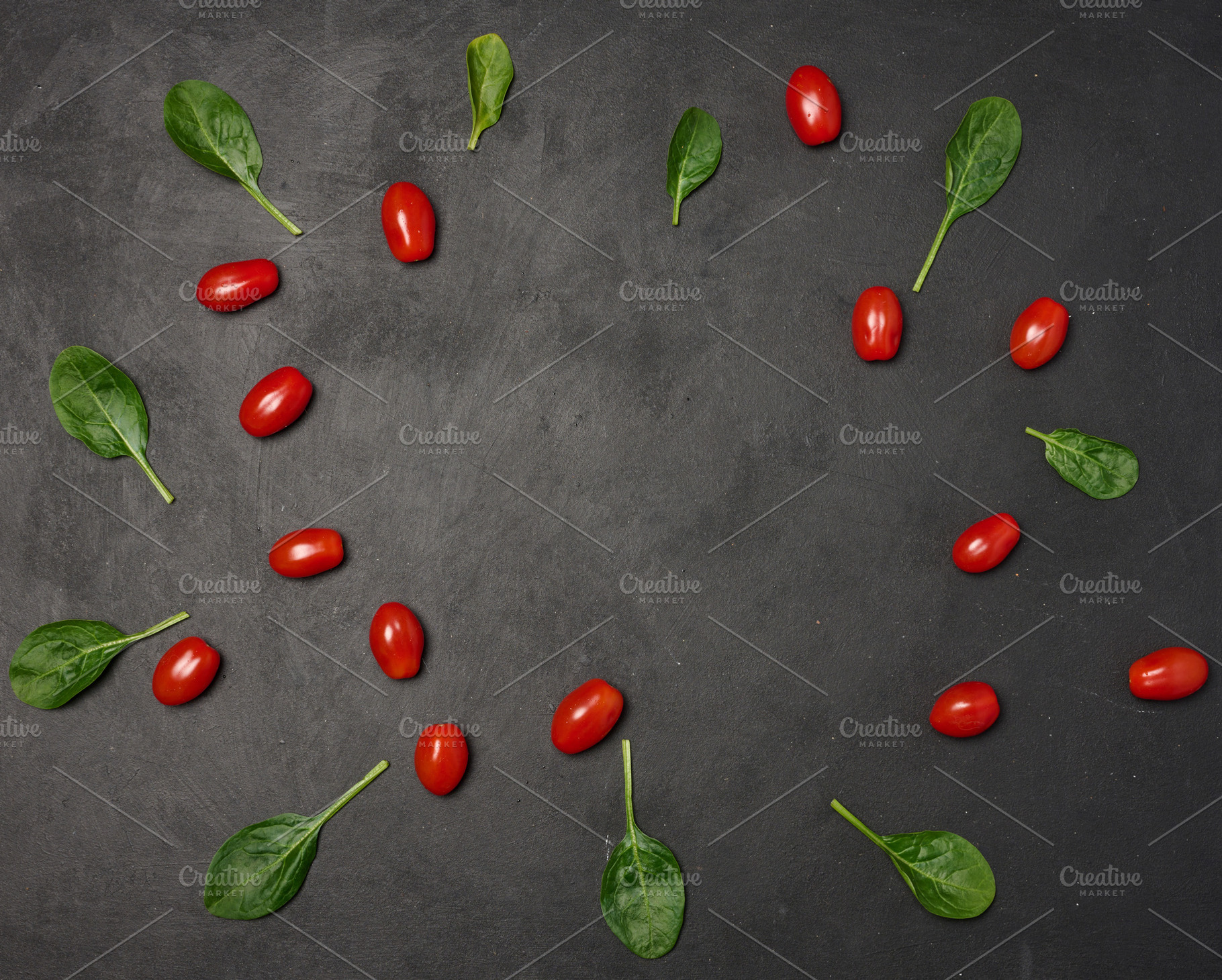 Scattered spinach leaves and red cherry tomatoes on black backgr, a Food & Drink Photo by ndanko