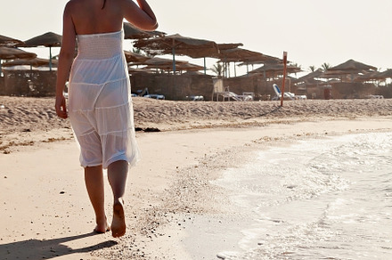 Young woman in white dress walking along the seashore, a Person Photo by TanaCh