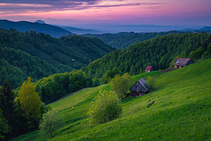 Wooden huts on the slope at sunset, an Architecture Photo by Alpine Dreams