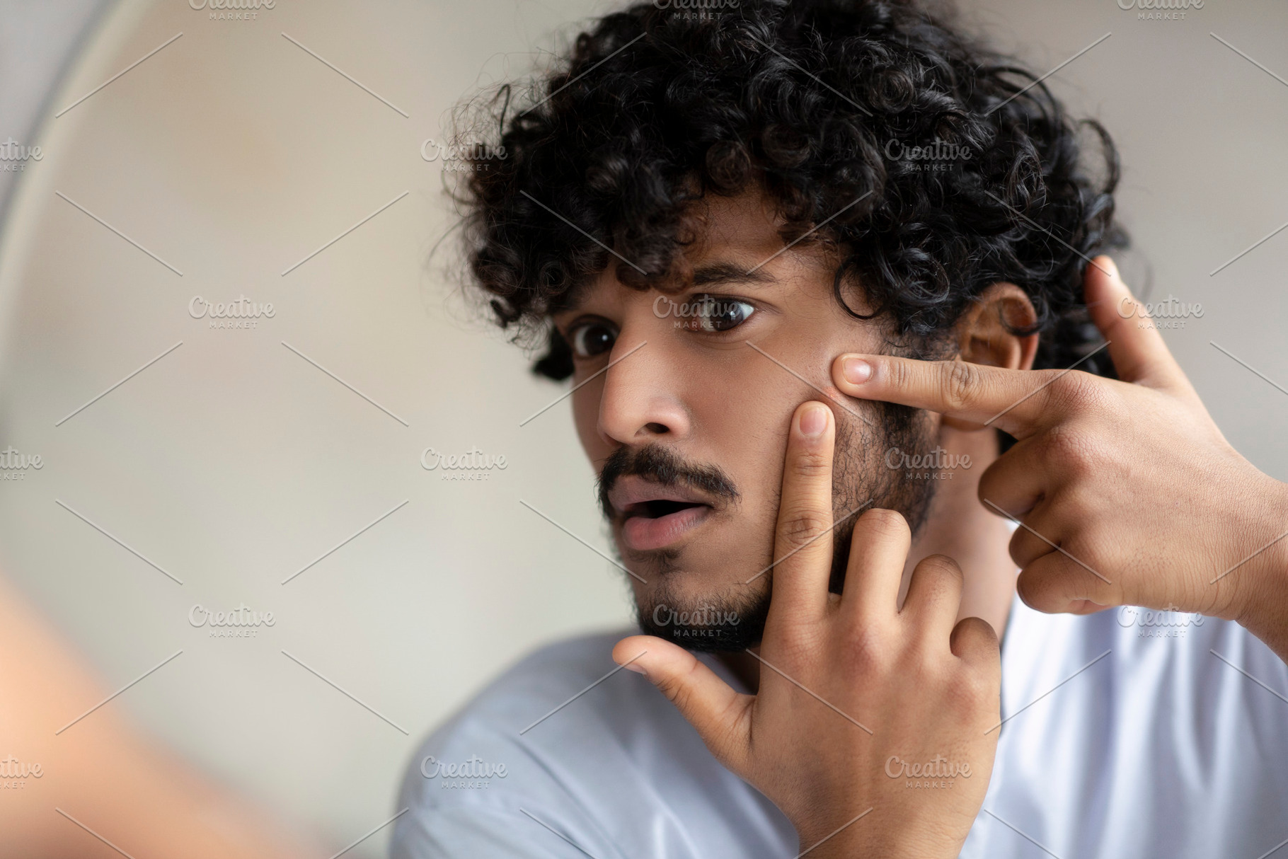 Portrait of handsome indian man touching his face, pressing pimple on face with, a Person Photo by Prostock-Studio