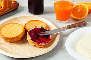 Spreading blueberry jam on toasted bread for breakfast with orange juice and bu, a Food & Drink Photo by Antonio Gravante Market