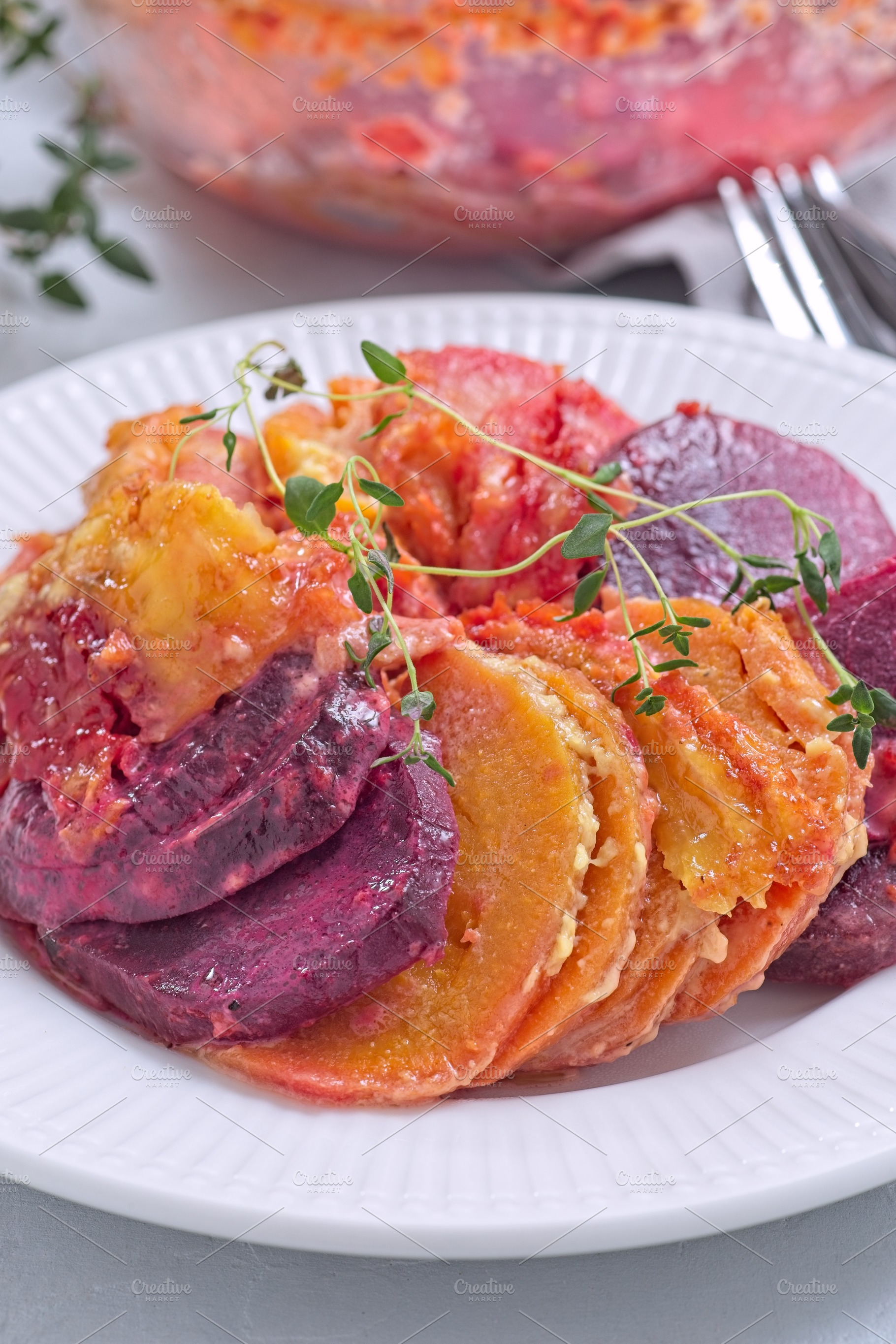 Sweet potato, parsnips and beet root gratin with thyme and melted cheese, on wh, a Food & Drink Photo by iuliia_n