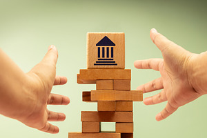 Hands reaching toward unstable wooden blocks with government ban, a Photo by salmon.black