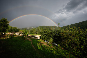A scenic rural landscape with a vibrant double rainbow over rolling green hills, a Photo by AS photostudio