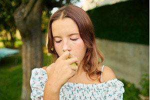 Girl eating a pear while standing in