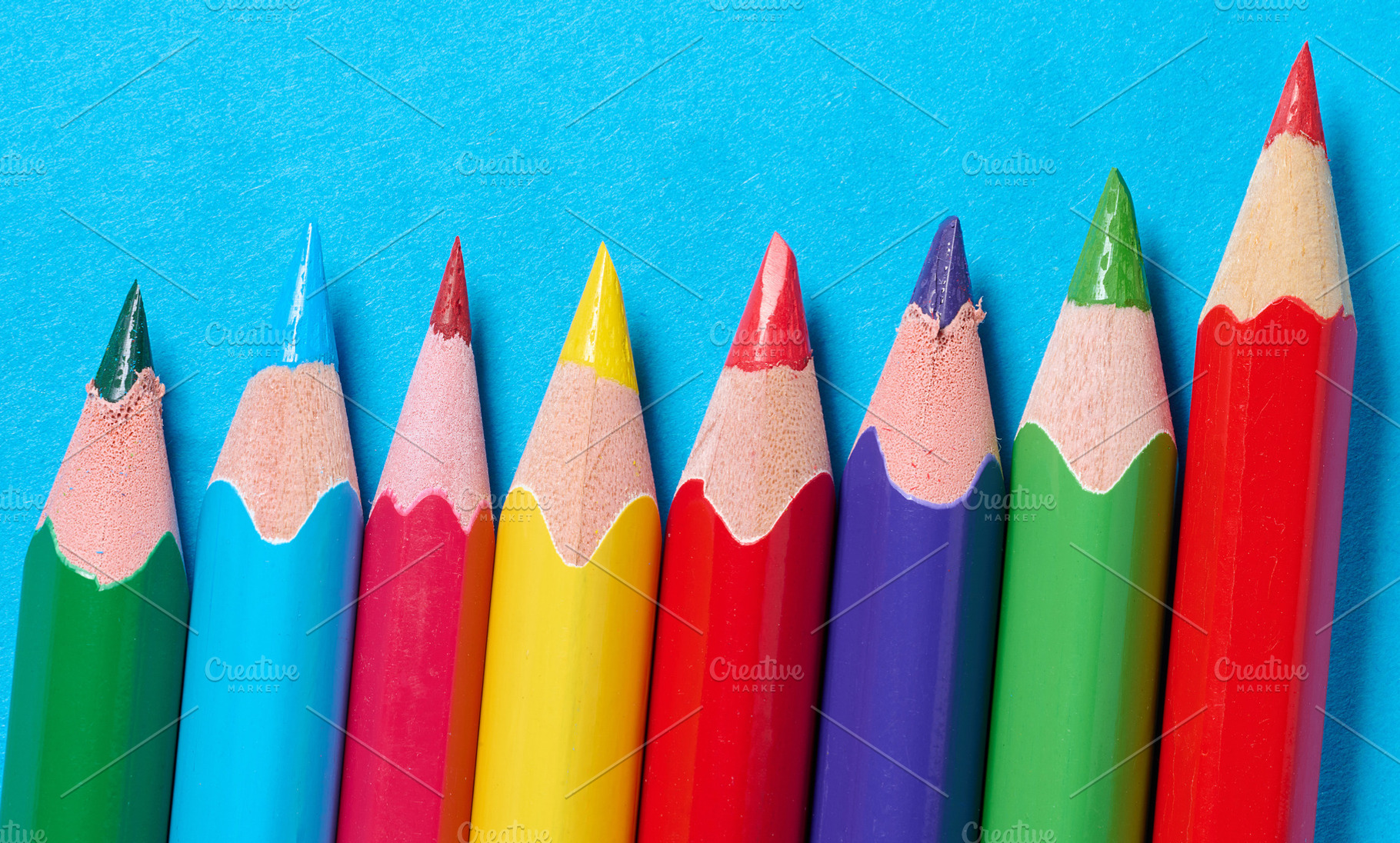 A row of sharpened colored pencils arranged diagonally on a blue, a School & Education Photo by ndanko