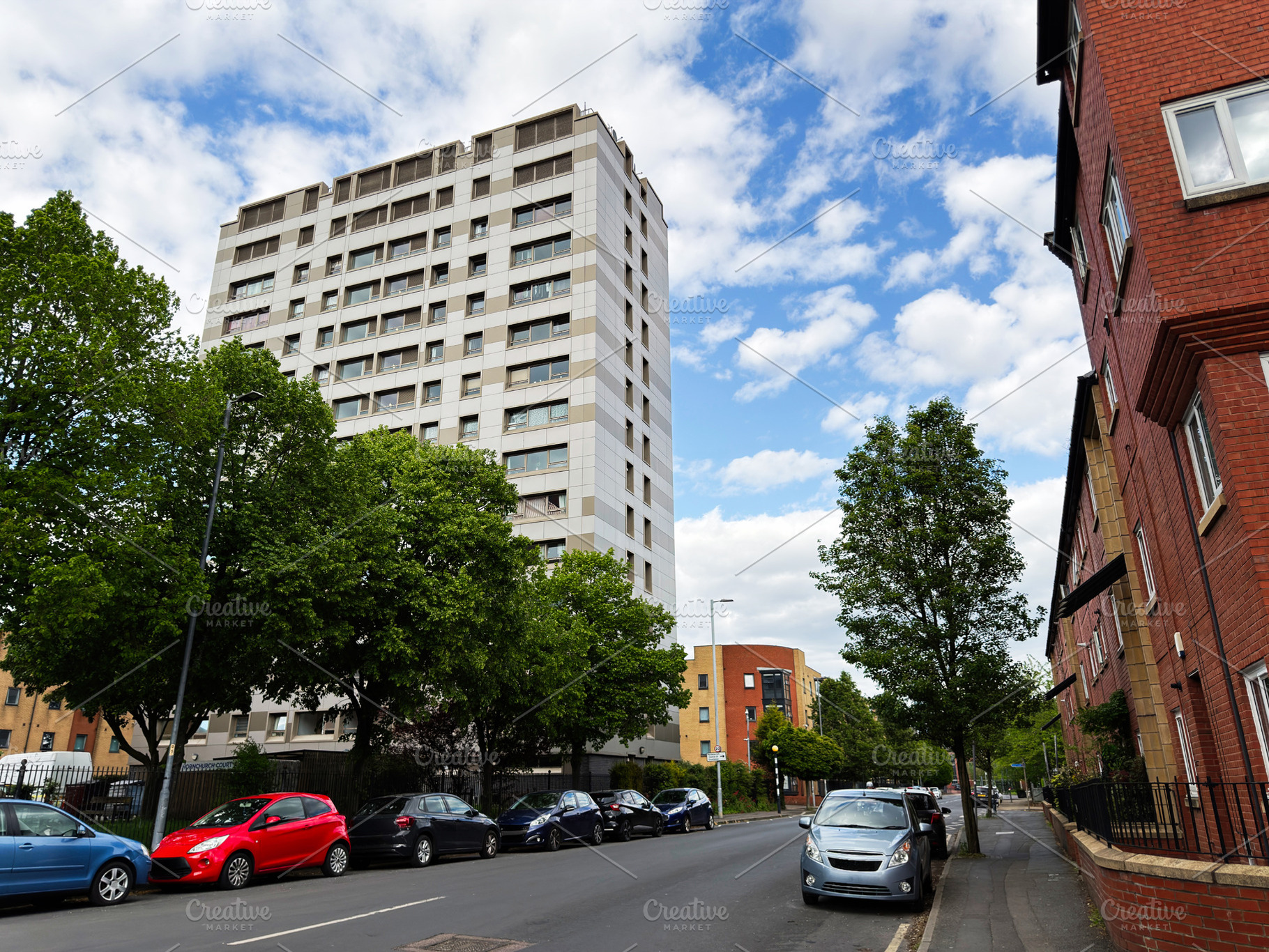 Residential apartment building and parked cars on a tree lined u, a Photo by AS photostudio
