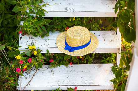 The straw hat on the wooden staircase is surrounded by greenery, a Beauty & Fashion Photo by Artsaba Family