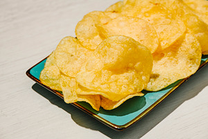 golden potato chips on a turquoise rectangular plate, a Photo by Nito