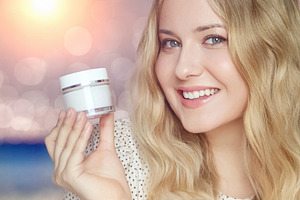 Young blonde woman smiling, holding skincare cream jar for beaut, a Person Photo by Studio ANNA