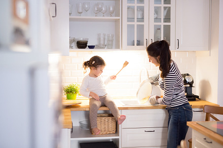 Mother with her daughter in the kitchen cooking together featuring child