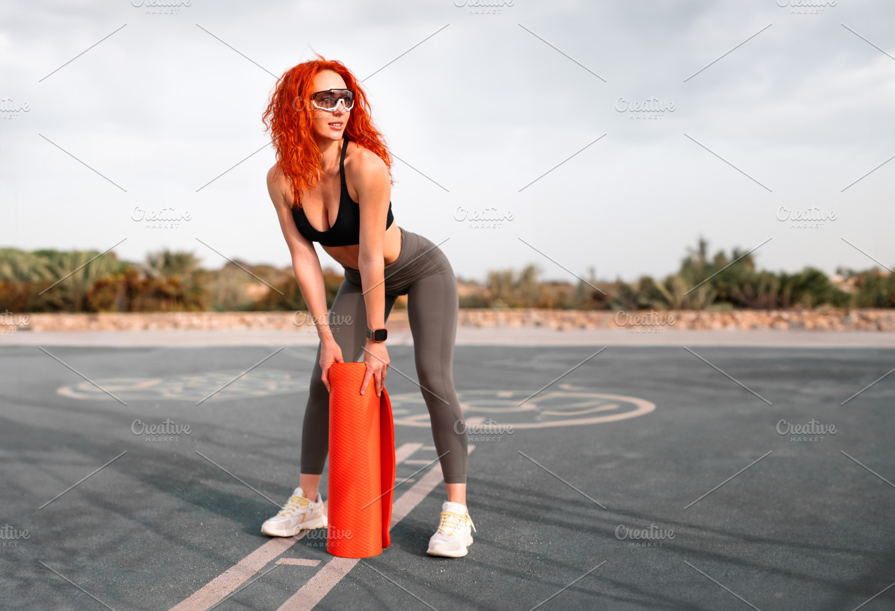 Sensuous jogger woman holding rolled up exercise mat at outdoor gym, a Person Photo by andreonegin market