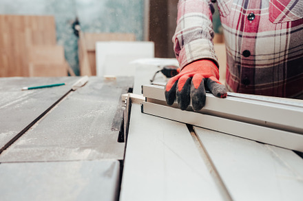 Carpenter cuts plywood on a circular, a Photo by borodai94