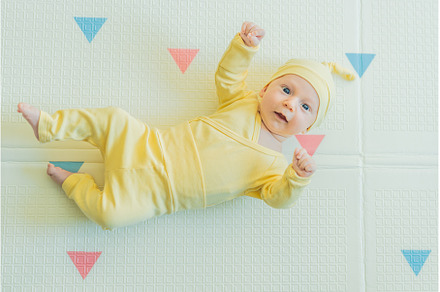 Adorable baby in a yellow hat lying