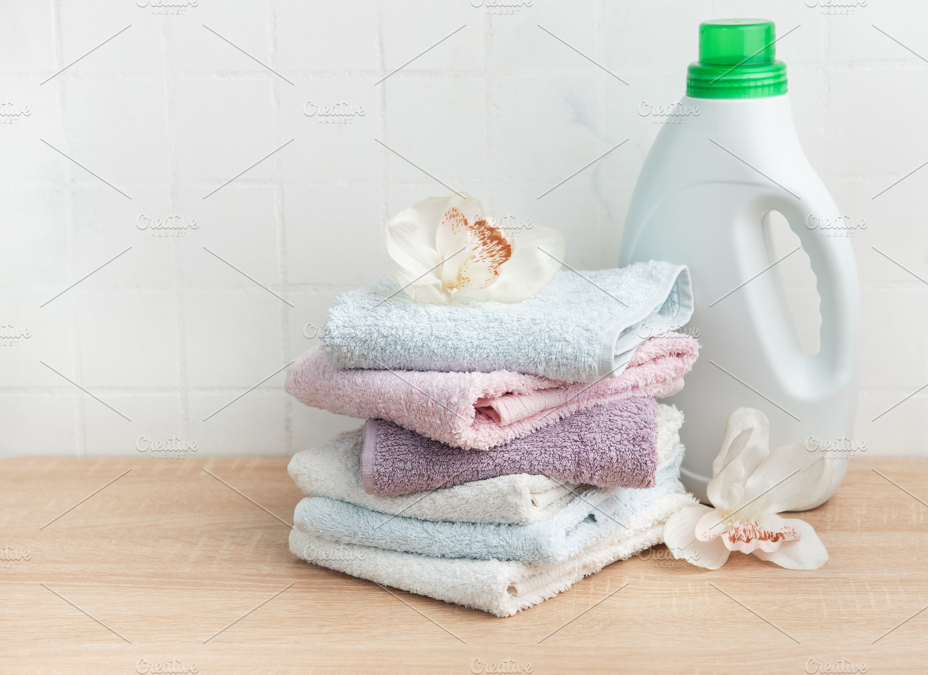 Stack of clean towels with laundry detergent bottle, an Industrial Photo by Olena Rudo