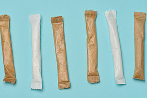 White and brown paper sticks with sugar, arranged in a row on a, a Food & Drink Photo by ndanko