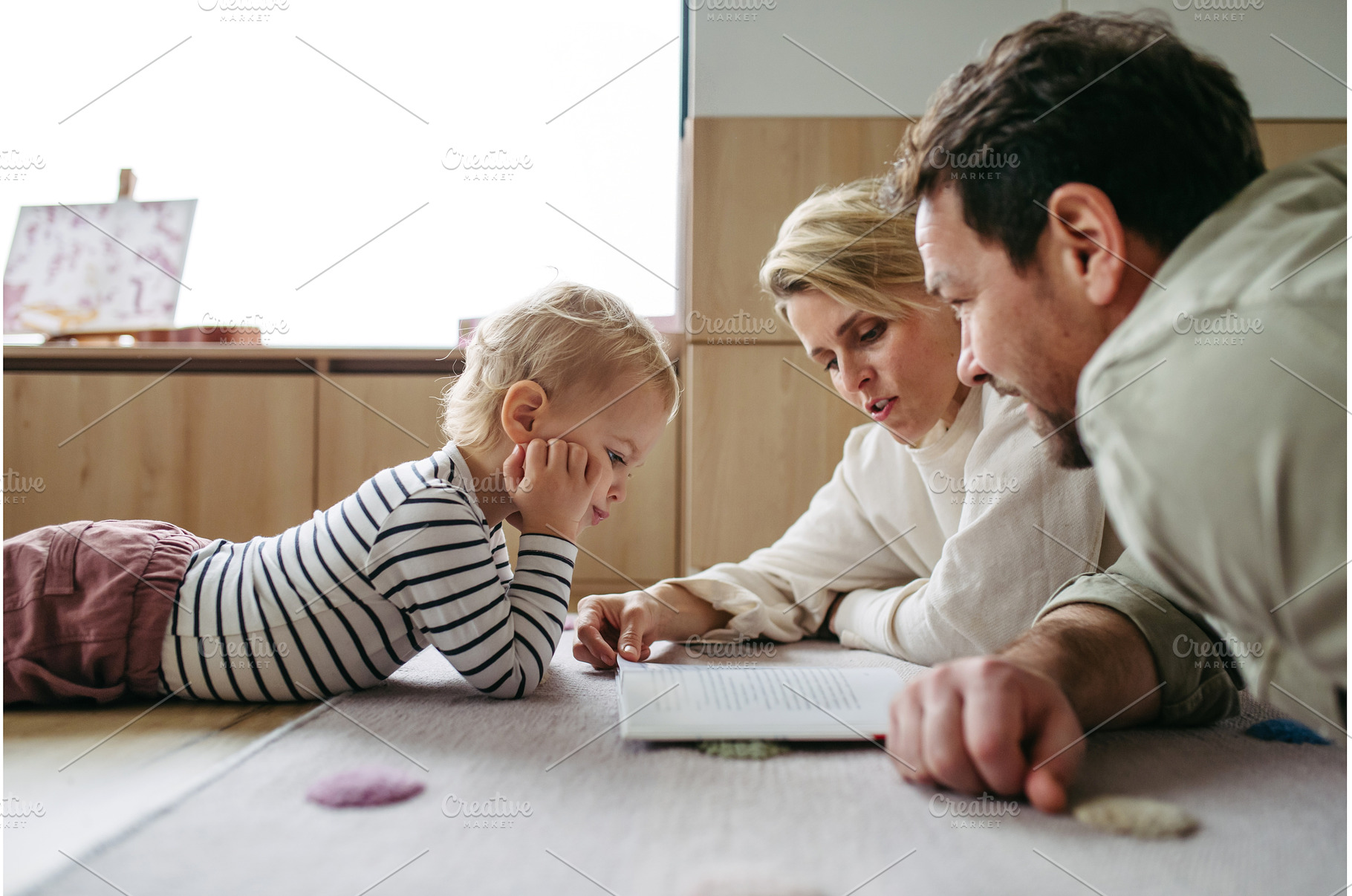 Parents reading book with little son, a Person Photo by HalfPoint