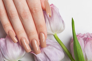 Woman showing beige manicure near bouquet of purple tulips, a Beauty & Fashion Photo by Olena Rudo