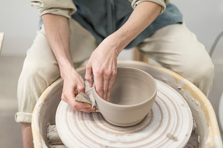 Female ceramic artist in apron working in pottery workshop