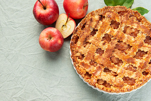 Freshly baked apple pie with red apples and leaves on green tabl, a Food & Drink Photo by Olena Rudo