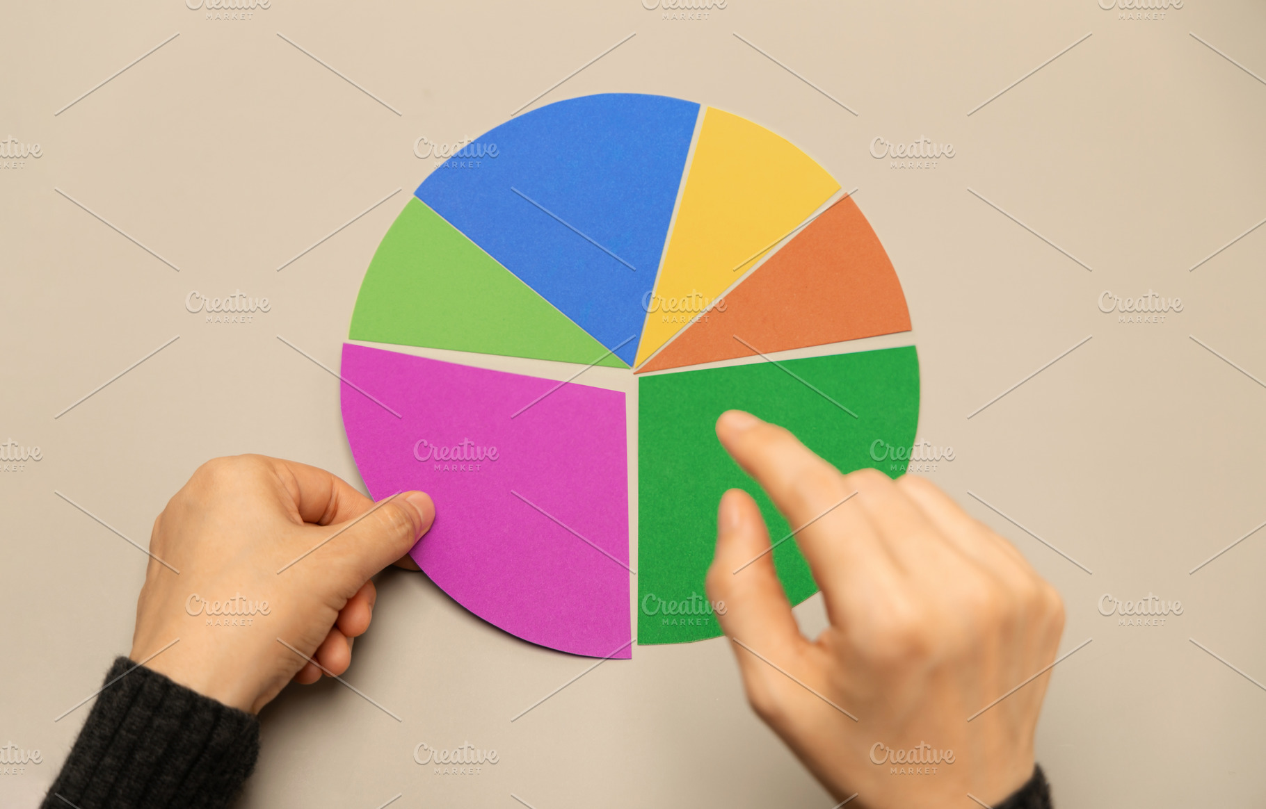 Hand selecting a segment on a colorful pie chart representing da, a Photo by salmon.black