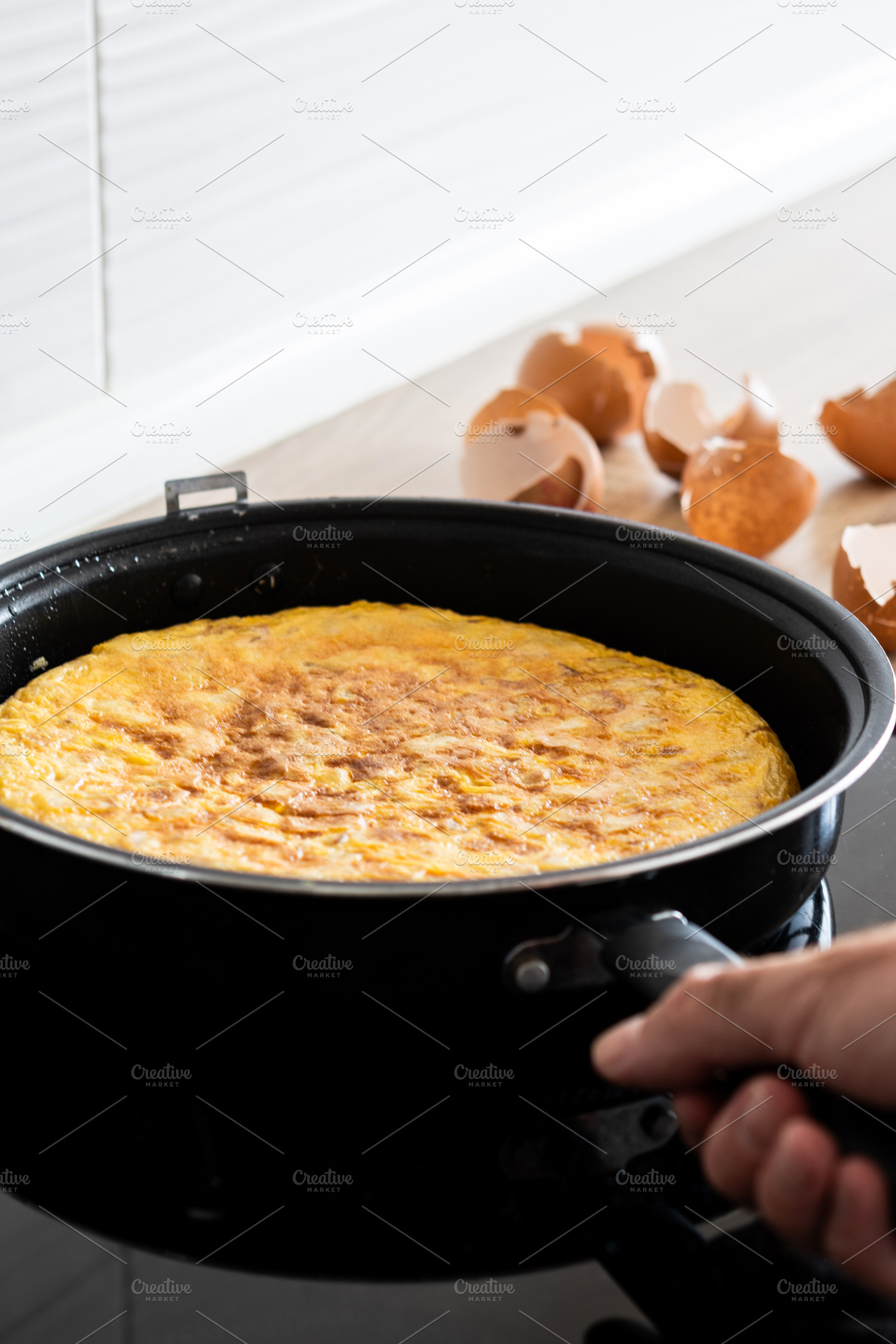 Hand holding frying pan with Spanish potato omelette, a Photo by etorres69