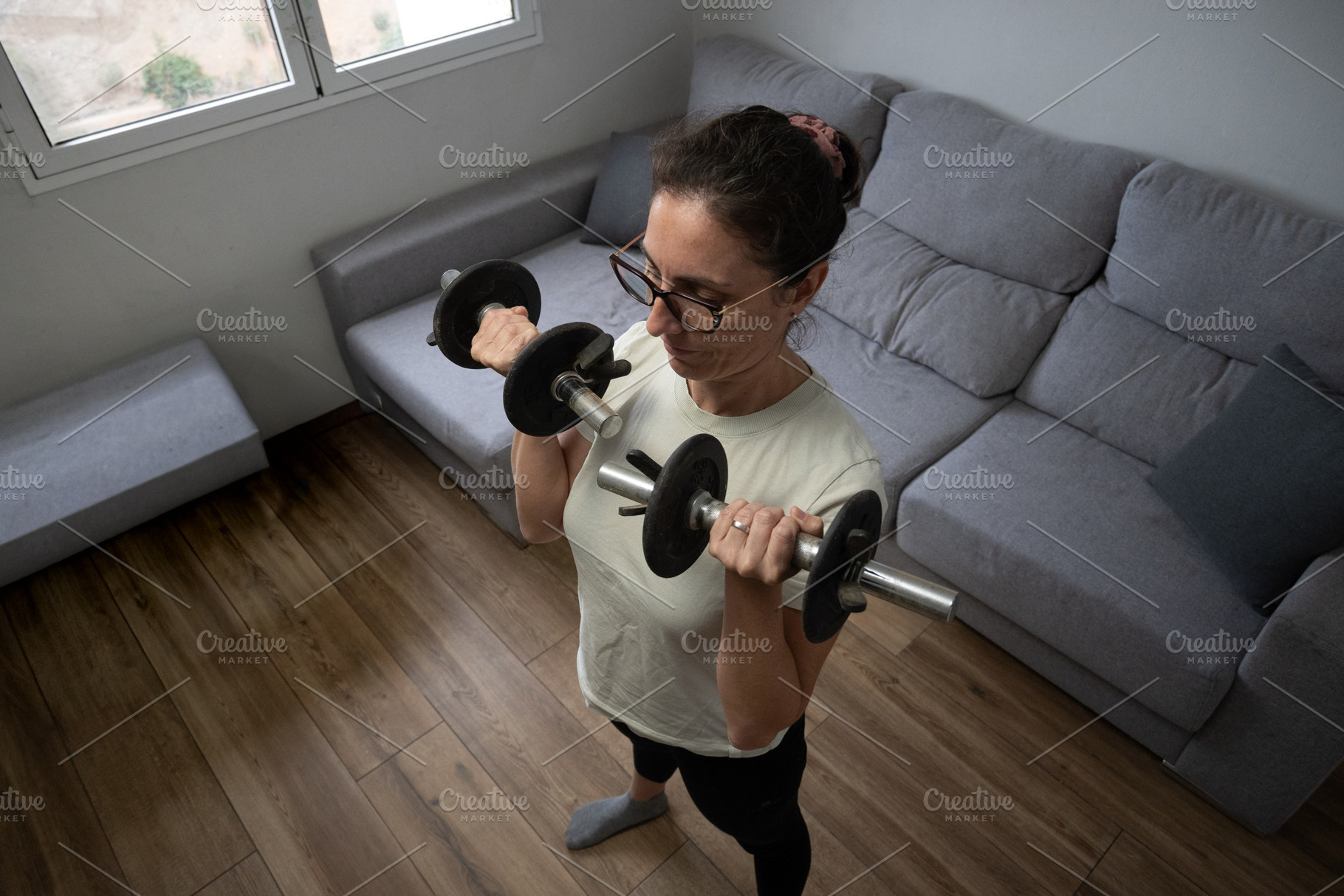 Woman doing triceps exercise with dumbbell at home, a Person Photo by etorres69