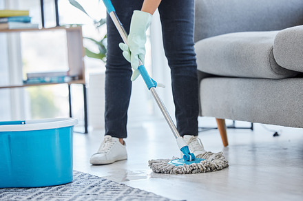 Mop, flooring and woman cleaning living room house, home and apartment. Cleaner, maid and housekeeping service on wet ground, care and safety of virus, bacteria and dust for household disinfection, a Photo by Peopleimages.com
