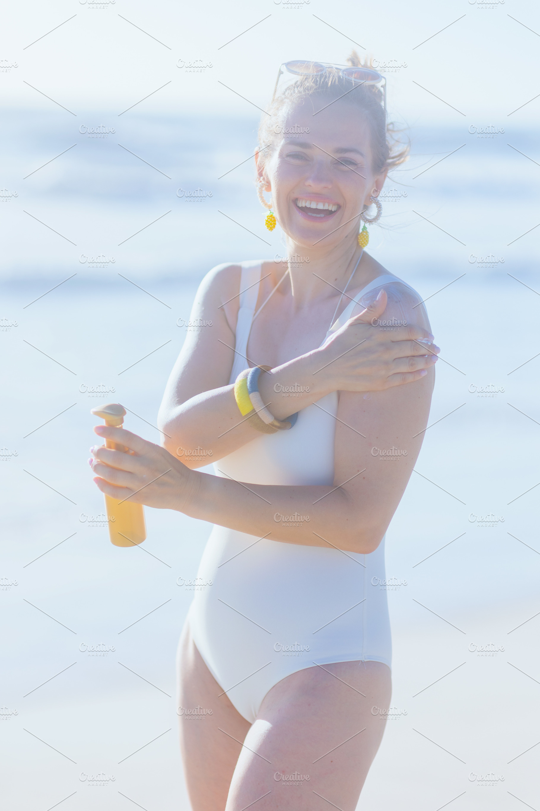 happy elegant woman in swimwear at beach applying sunscreen, a Person Photo by Alliance Images