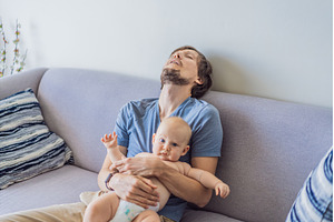 Tired father falling asleep on couch, a Person Photo by Elizaveta Galitskaya