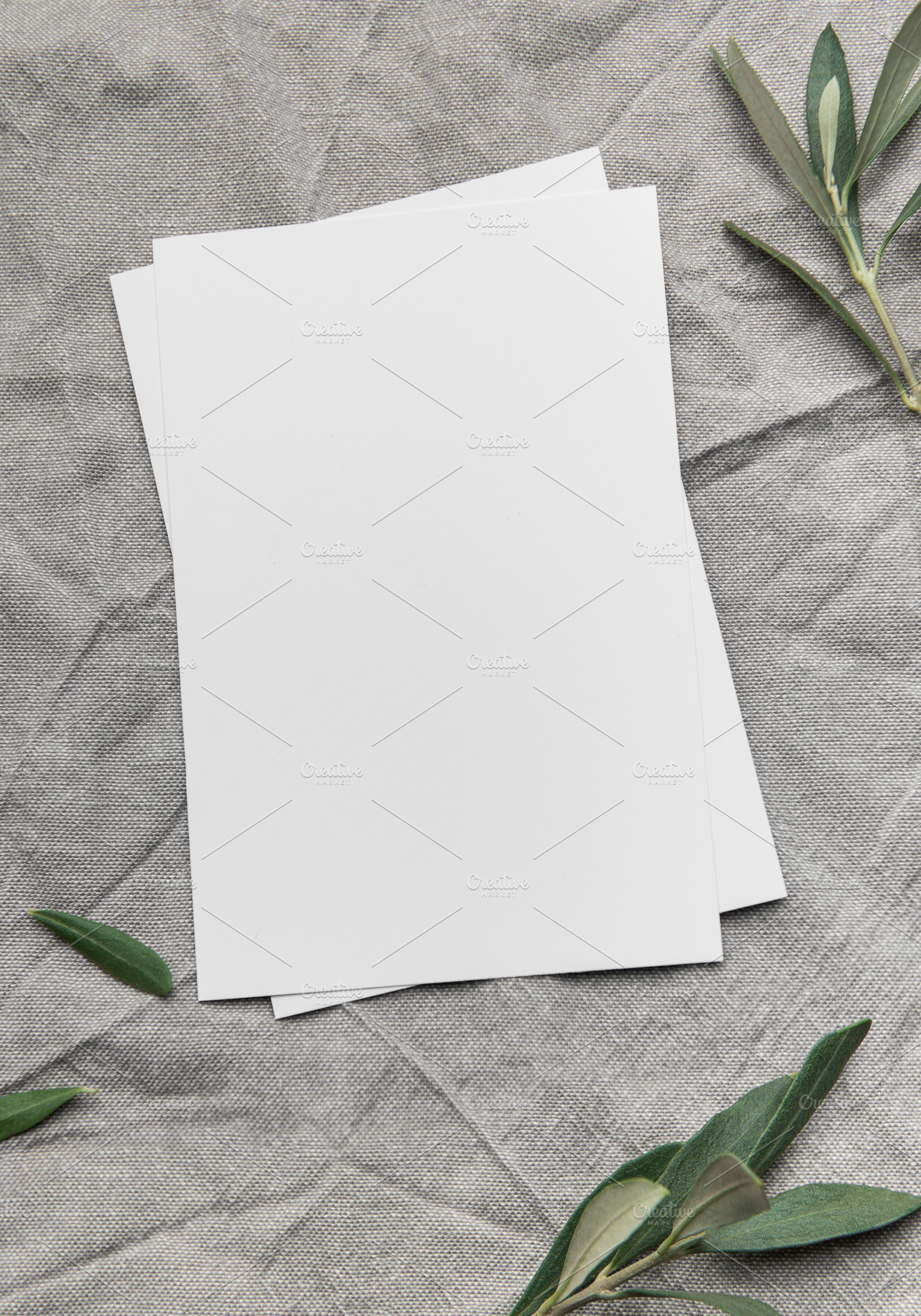 Blank cards with olive branches resting on gray linen fabric, a Background Photo by Olena Rudo