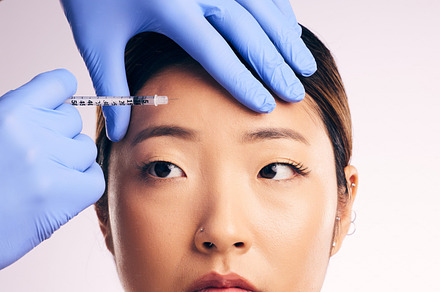 Forehead injection, face skincare and Asian woman in studio isolated on a white background. Cosmetics, syringe and female model with collagen filler, dermatology and prp facelift in plastic surgery., a Photo by Peopleimages.com