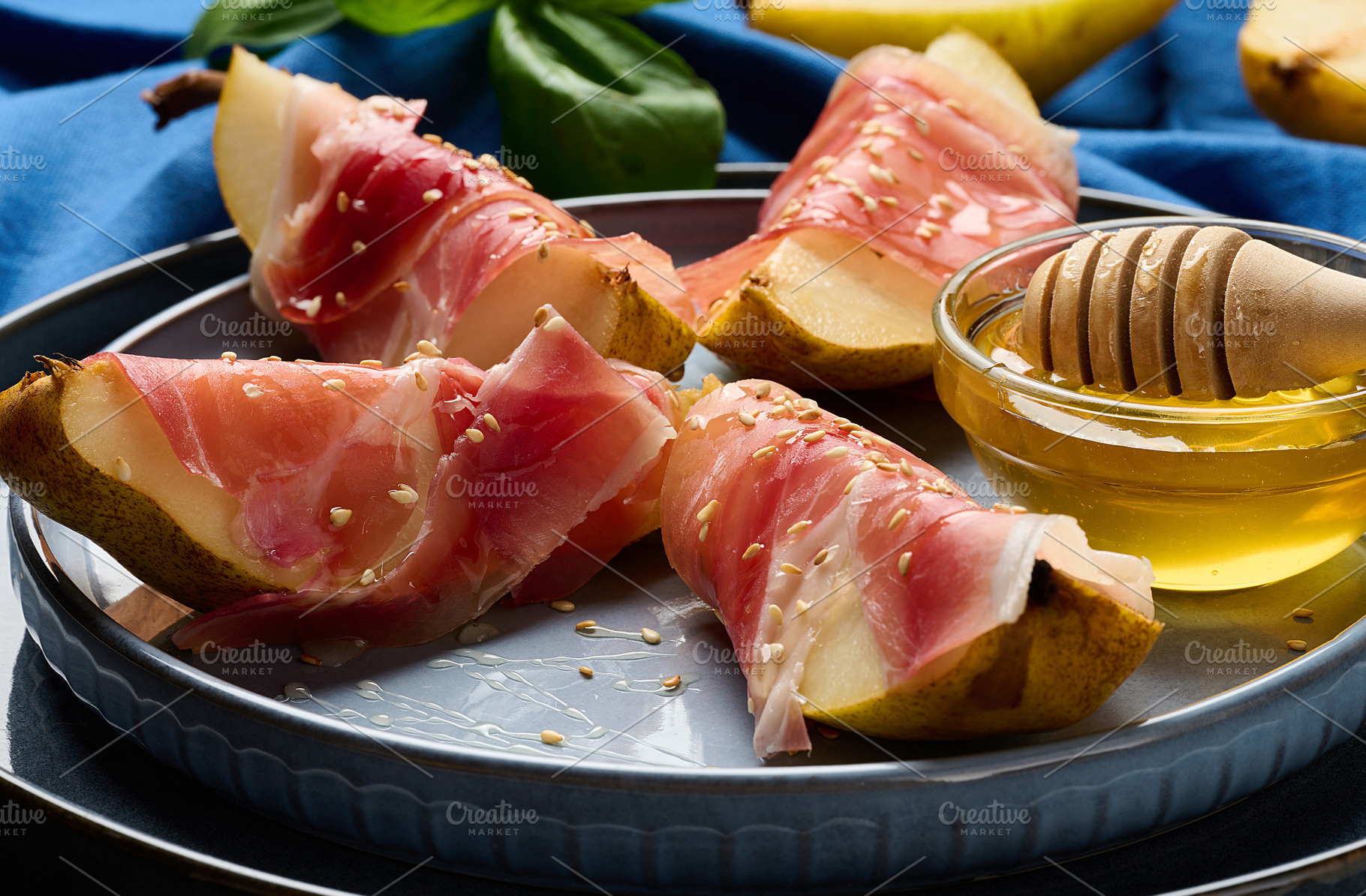 Gourmet appetizer of pear with prosciutto and sesame seeds, serv, a Food & Drink Photo by ndanko