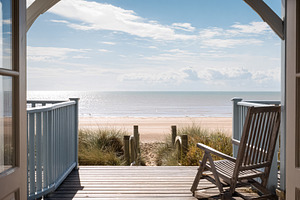 Wooden deck and open doors of a beach house offering a serene vi, a Photo by Studio ANNA