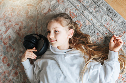 Little girl listening music lying on the floor, a Person Photo by Olena Rudo