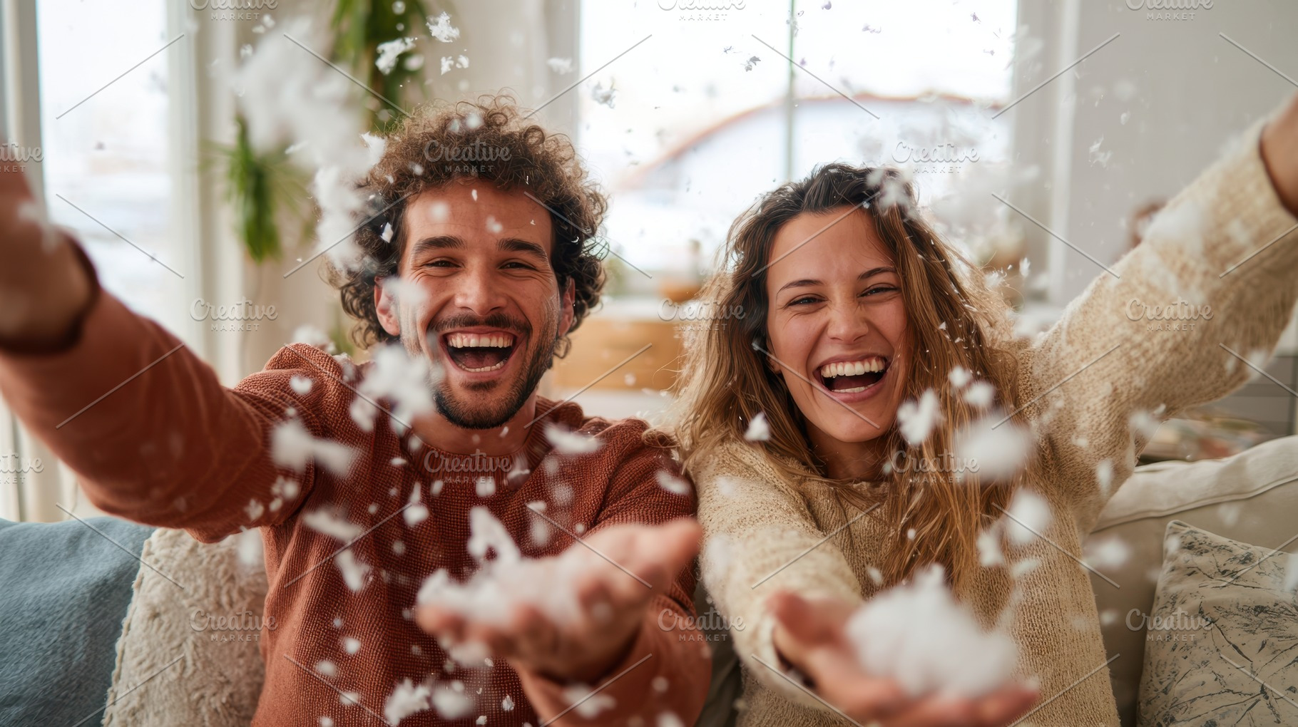 Joyful couple playing with fluff from the pillow indoors, a Person Photo by AlyaAnd