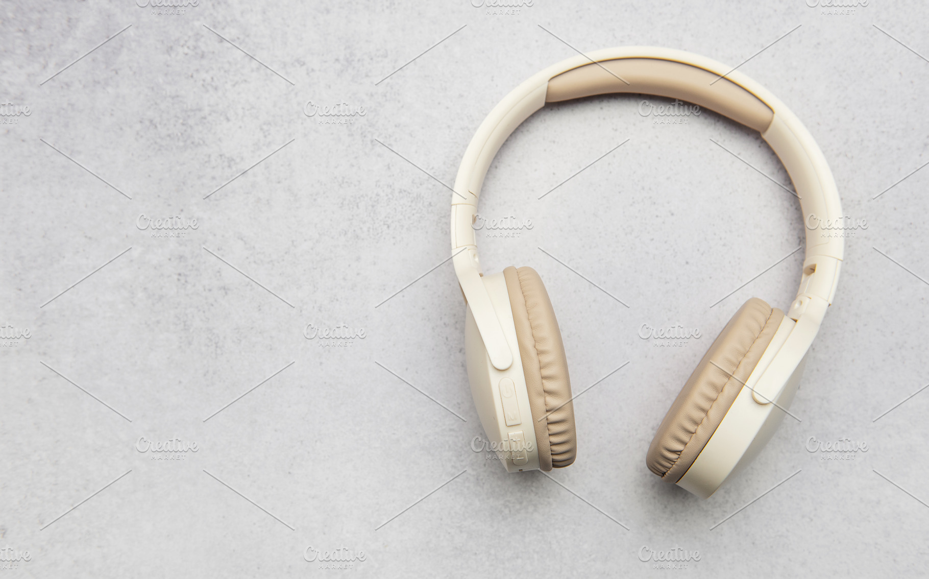 Modern wireless headphones lying on gray stone background, a Business Photo by Olena Rudo
