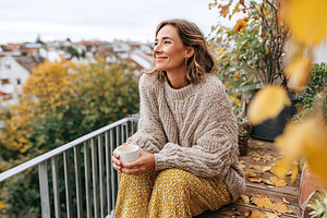 Enjoying warm tea on a cozy balcony while wrapped in loose clothing during autu, a Person Photo by AlyaAnd