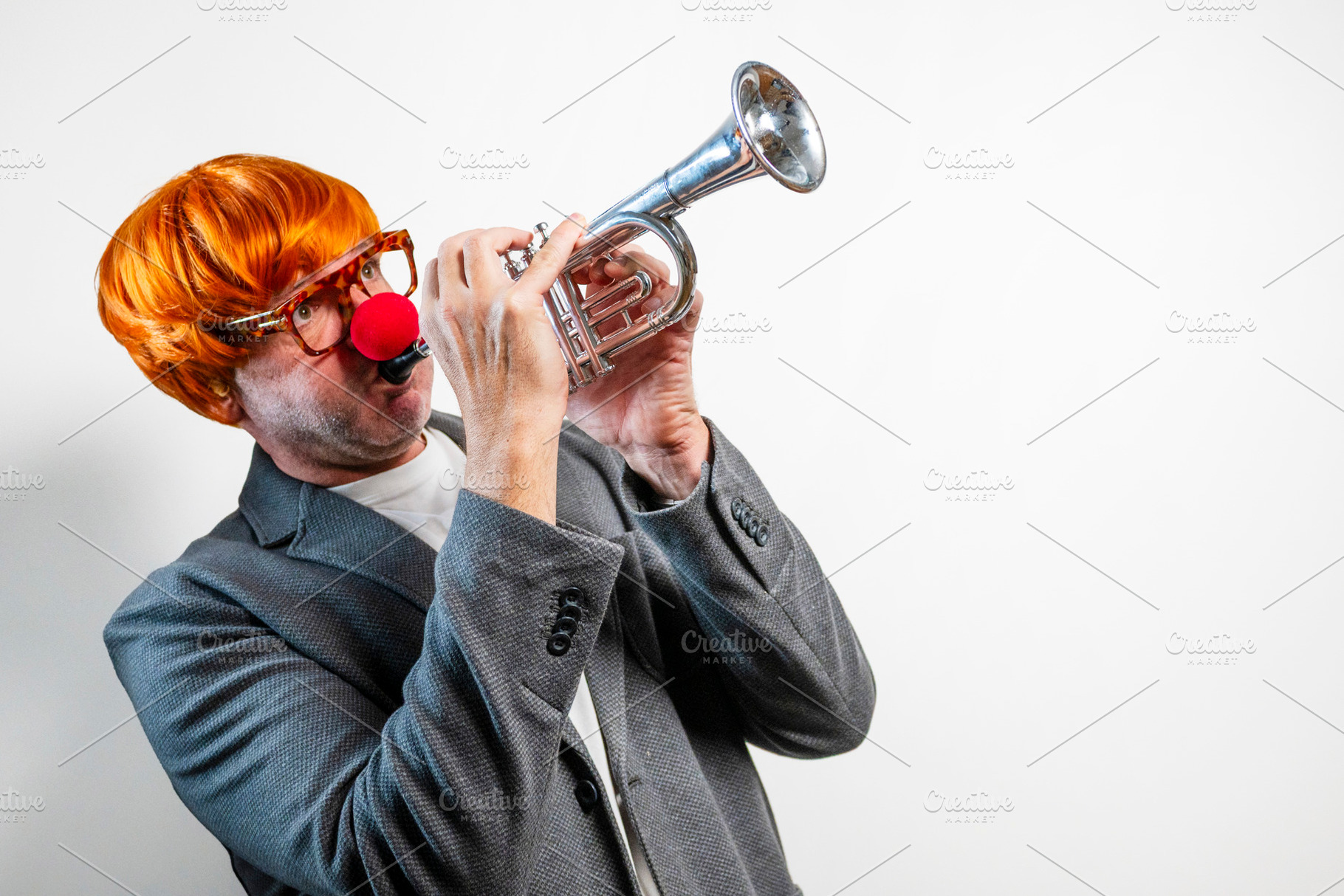 Clown playing trumpet with red nose and wig, a Person Photo by karrastock