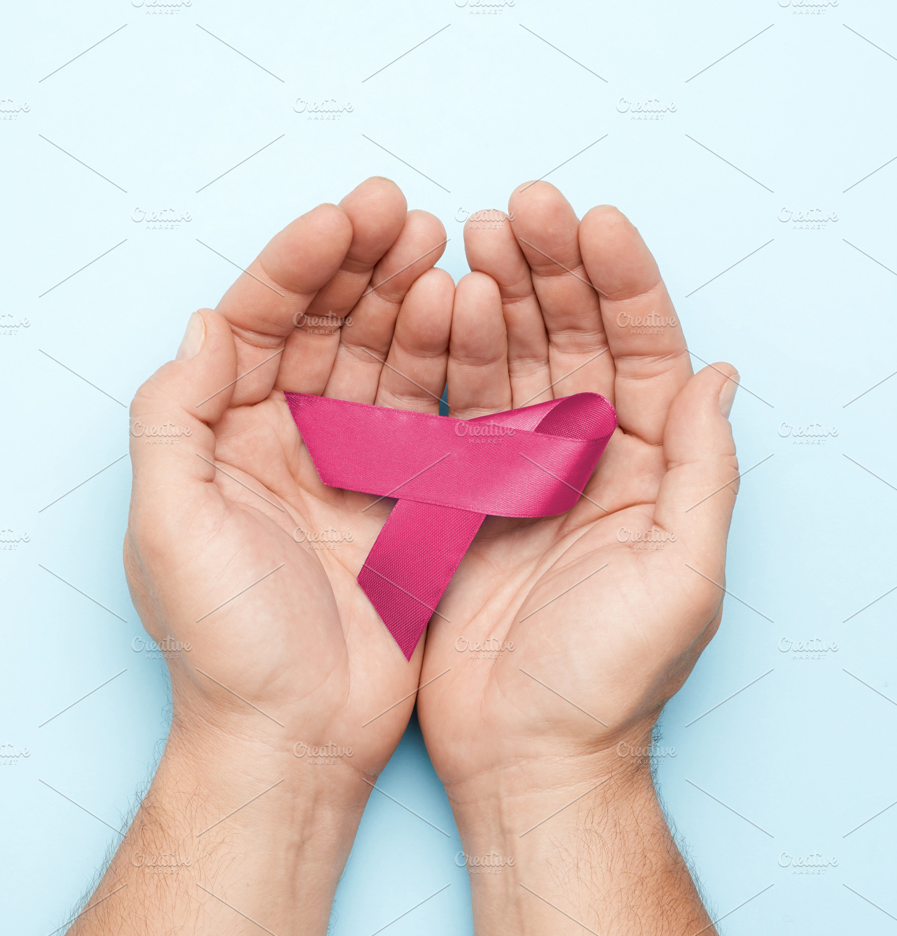 Male hands holding a pink ribbon, symbol of breast cancer awaren, a Person Photo by ndanko